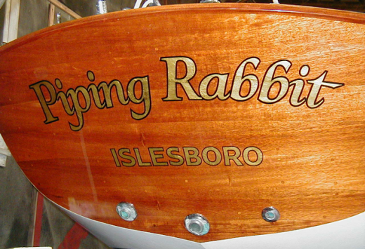 Piping Rabbit in gold on mahogany.