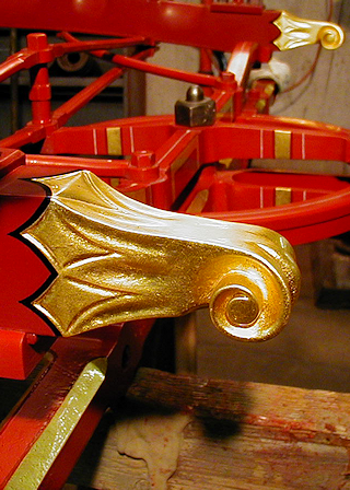 Gilded carved wood frame ends on 1880s Silsby hose carriage.